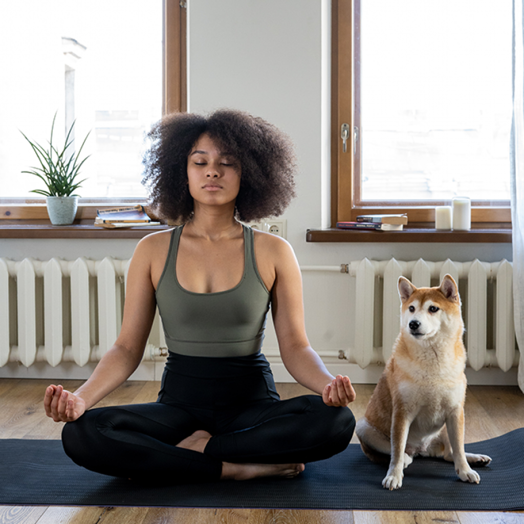 woman meditating on yoga mat with dog