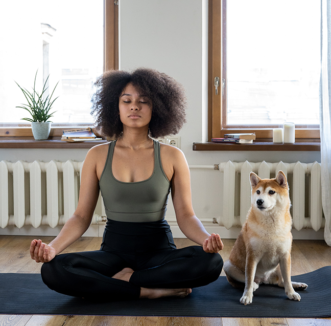 woman meditating on yoga mat with dog
