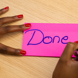 hand holding pen over pink card with the word "Done"